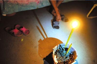 26日,芦山县龙门乡隆兴村村民张德文在帐篷中点燃香烛。他的妻子在地震中不幸遇难。 新华社发